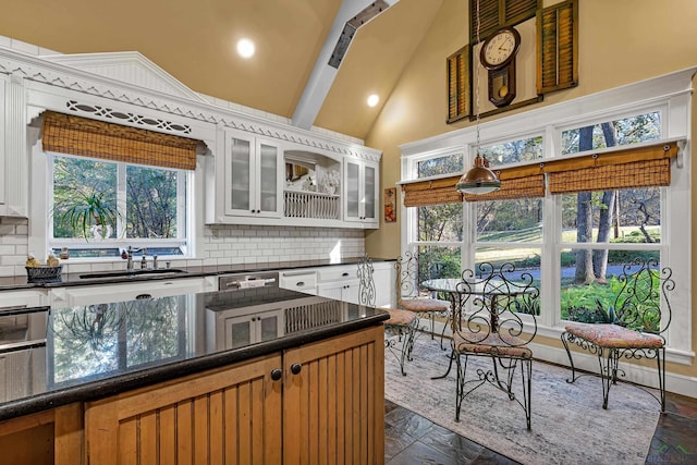 kitchen featuring decorative backsplash, white cabinetry, sink, and high vaulted ceiling