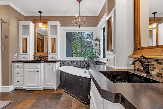 bathroom featuring vanity, backsplash, a bathing tub, ornamental molding, and a chandelier