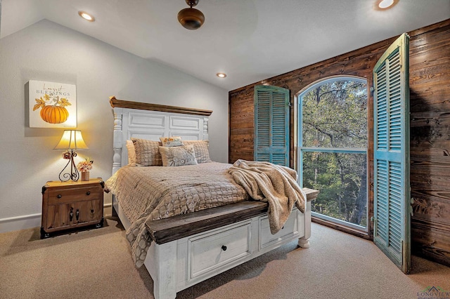 carpeted bedroom featuring ceiling fan, lofted ceiling, and wood walls