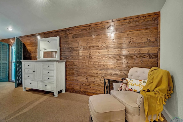 living area with carpet floors, a textured ceiling, and wooden walls