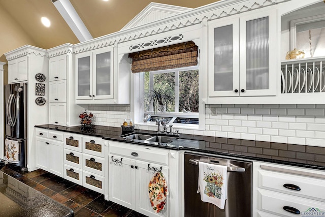 kitchen featuring appliances with stainless steel finishes, tasteful backsplash, sink, white cabinets, and lofted ceiling