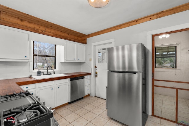 kitchen featuring light tile patterned floors, appliances with stainless steel finishes, white cabinets, and sink