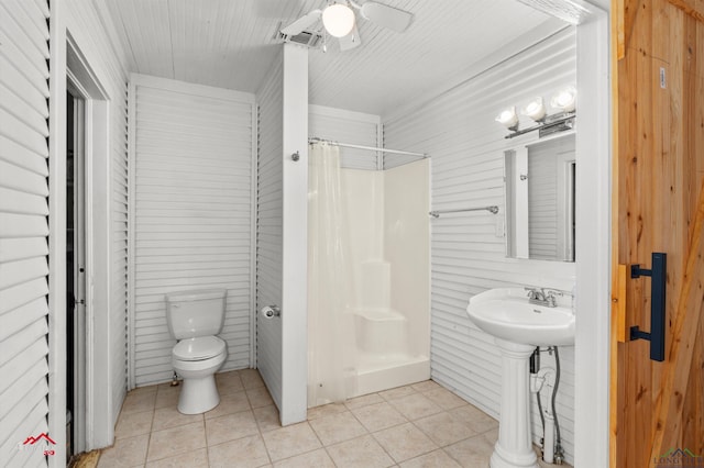 bathroom featuring toilet, tile patterned floors, wooden walls, and curtained shower