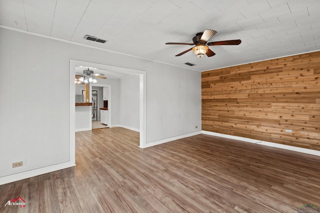 spare room featuring ceiling fan, hardwood / wood-style floors, and wooden walls