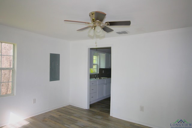 empty room featuring electric panel, ceiling fan, sink, and dark wood-type flooring