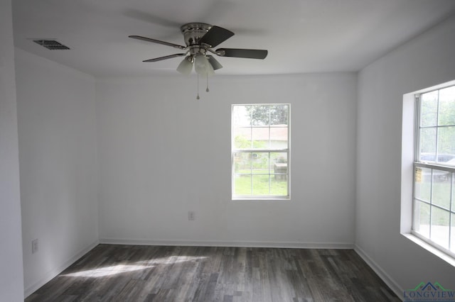 empty room with dark hardwood / wood-style flooring, plenty of natural light, and ceiling fan