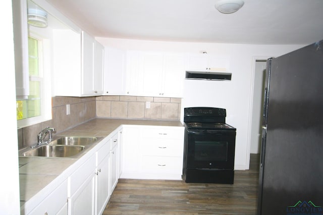 kitchen with stainless steel refrigerator, black range with electric stovetop, white cabinetry, sink, and backsplash