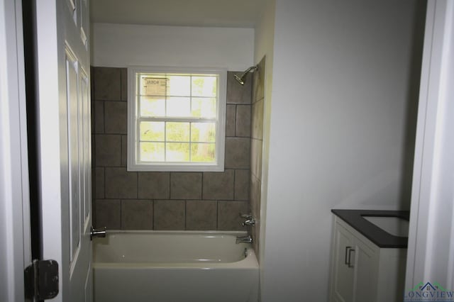 bathroom with tiled shower / bath combo and vanity