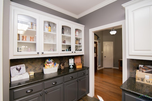 bar featuring decorative backsplash, dark stone counters, dark wood-type flooring, gray cabinets, and white cabinetry