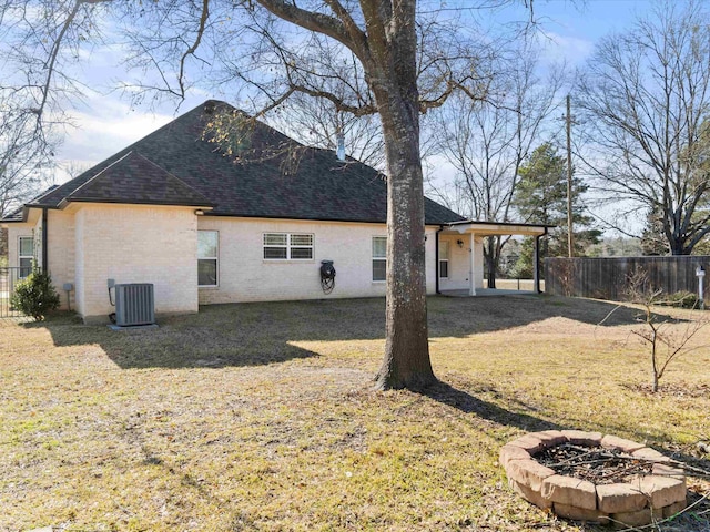 rear view of property featuring cooling unit, a fire pit, and a yard