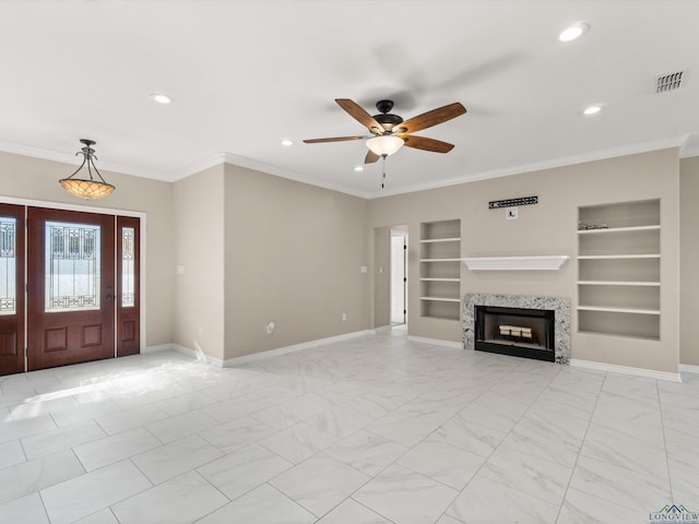 unfurnished living room with a fireplace, ceiling fan, built in shelves, and ornamental molding