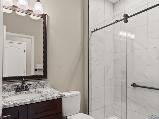 bathroom with toilet, vanity, and a shower with shower door