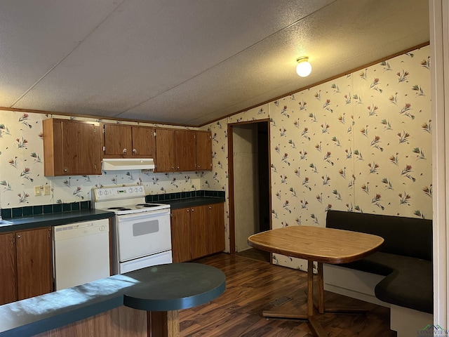 kitchen featuring dark wood-type flooring, crown molding, vaulted ceiling, a textured ceiling, and white appliances