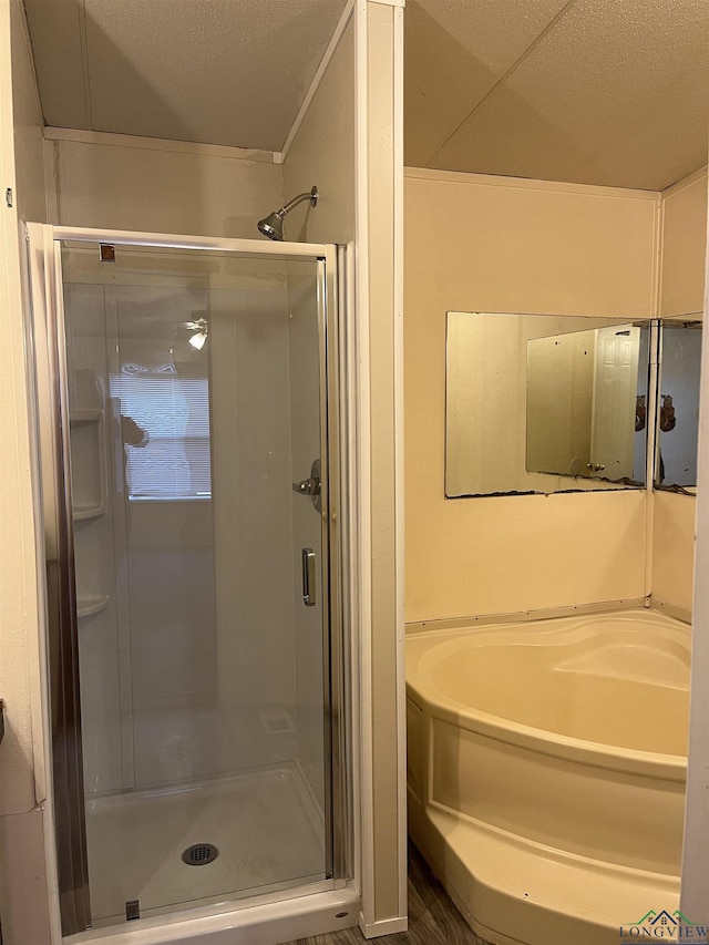 bathroom with a textured ceiling and shower with separate bathtub