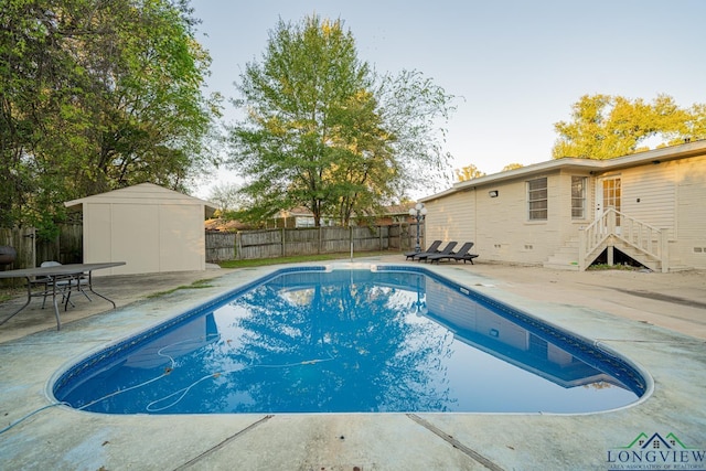 view of swimming pool with a storage unit and a patio area