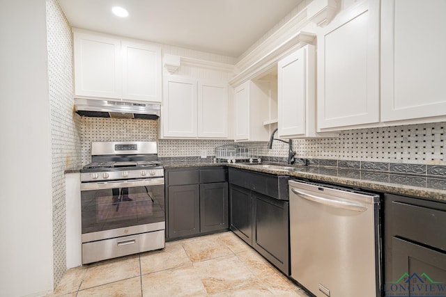 kitchen featuring sink, dark stone countertops, white cabinetry, stainless steel appliances, and extractor fan