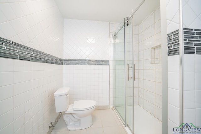 bathroom with tile patterned floors, toilet, tile walls, and walk in shower