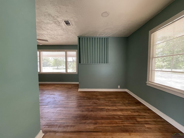 spare room featuring dark wood-type flooring, baseboards, and a textured ceiling