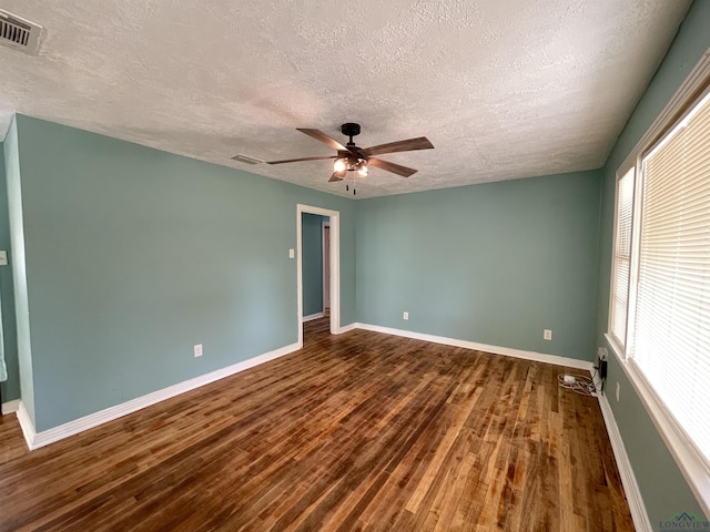 spare room featuring a textured ceiling, wood finished floors, a ceiling fan, and baseboards