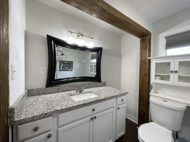 bathroom featuring toilet, vanity, wood finished floors, and a textured wall