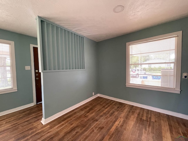 spare room featuring dark wood finished floors, baseboards, and a textured ceiling