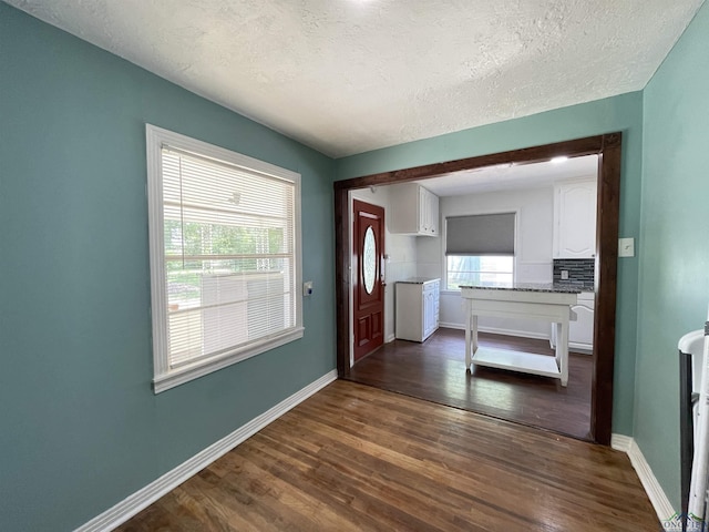 entrance foyer with dark wood-style floors, baseboards, and a textured ceiling