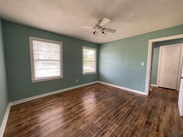 spare room featuring dark wood finished floors, baseboards, a textured ceiling, and a ceiling fan