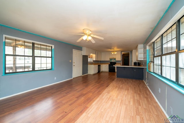 unfurnished living room featuring dark wood-style floors, ceiling fan with notable chandelier, and baseboards