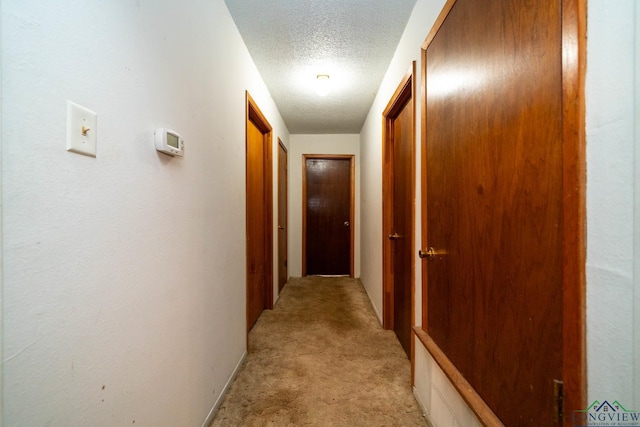 hall featuring a textured ceiling and light colored carpet