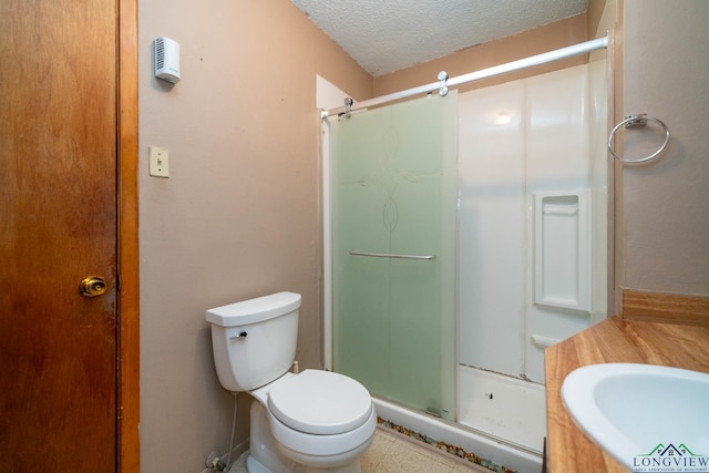 bathroom with a stall shower, a textured ceiling, toilet, and vanity