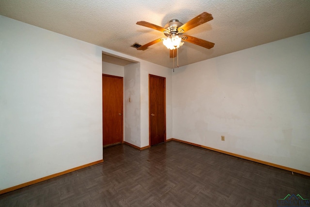 unfurnished room with a textured ceiling, ceiling fan, visible vents, and baseboards