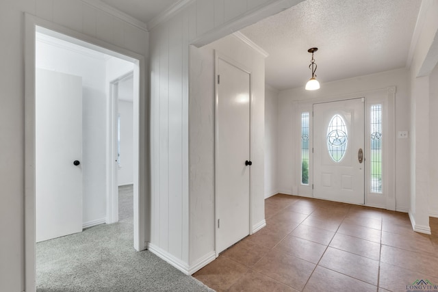 carpeted entryway featuring ornamental molding and a textured ceiling