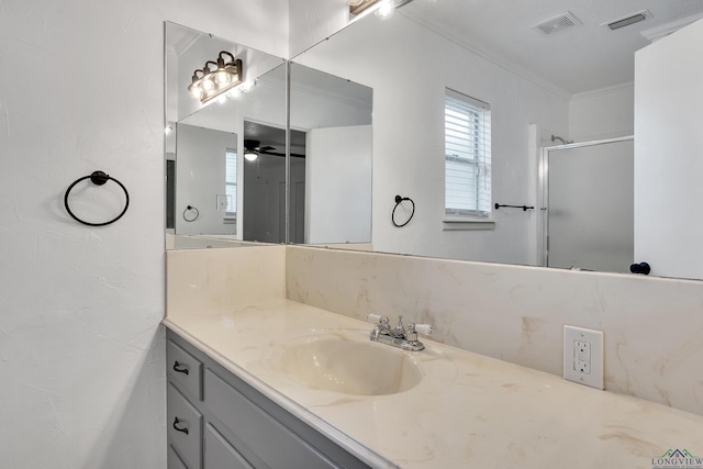 bathroom with ceiling fan, vanity, an enclosed shower, and ornamental molding