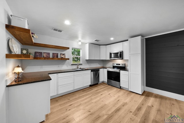 913 Church St, Winnsboro, TX 75494 - kitchen with stainless steel appliances, a sink, open shelves, light wood-style floors, and white cabinets