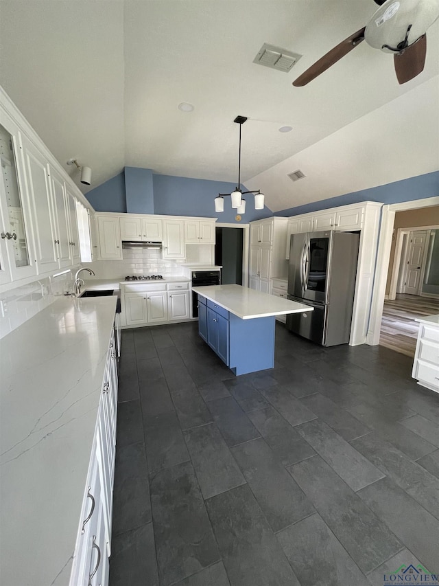 kitchen featuring a kitchen island, decorative light fixtures, lofted ceiling, white cabinets, and appliances with stainless steel finishes