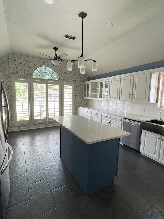 kitchen featuring stainless steel appliances, a center island, white cabinetry, hanging light fixtures, and lofted ceiling