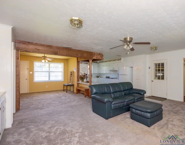 carpeted living room featuring ceiling fan and a textured ceiling