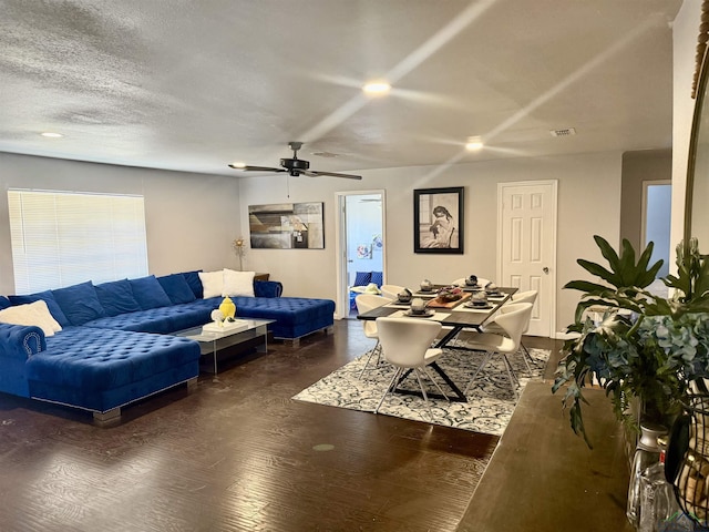 living room featuring a ceiling fan, visible vents, a textured ceiling, and wood finished floors