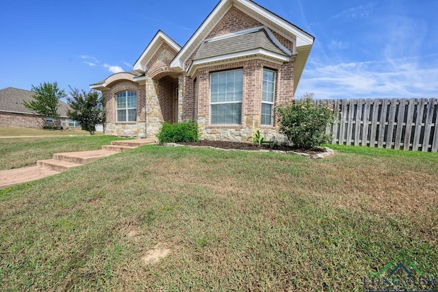 view of front of home featuring brick siding, a front yard, and fence