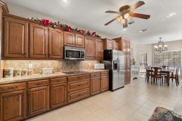 kitchen featuring tasteful backsplash, light stone counters, ceiling fan with notable chandelier, stainless steel appliances, and hanging light fixtures