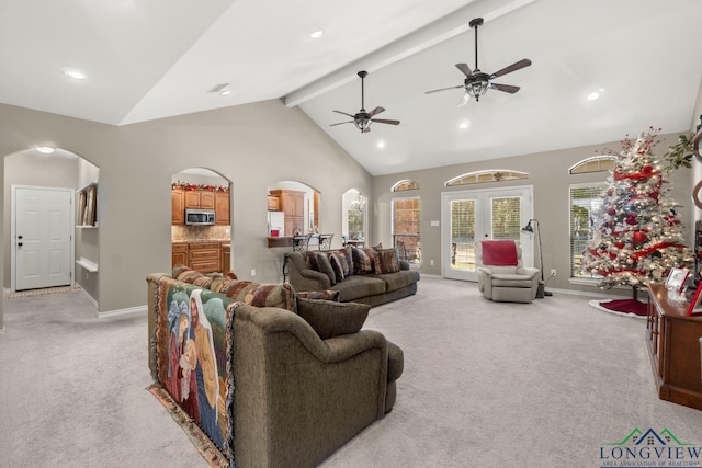 carpeted living room with beamed ceiling, high vaulted ceiling, and ceiling fan