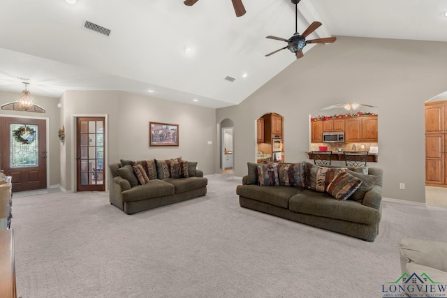 living room with ceiling fan, beam ceiling, light carpet, and high vaulted ceiling