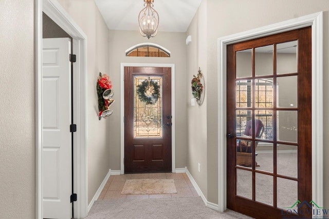 doorway with a chandelier, light tile patterned floors, and a healthy amount of sunlight