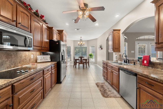 kitchen featuring appliances with stainless steel finishes, tasteful backsplash, ceiling fan with notable chandelier, sink, and light tile patterned flooring