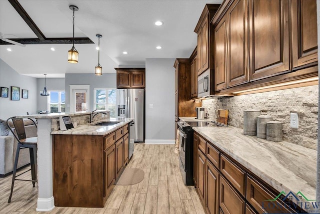 kitchen with backsplash, stainless steel appliances, sink, decorative light fixtures, and a breakfast bar area