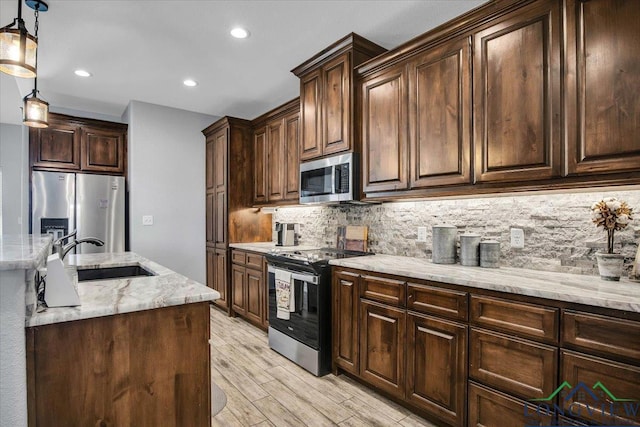 kitchen with appliances with stainless steel finishes, dark brown cabinets, and pendant lighting