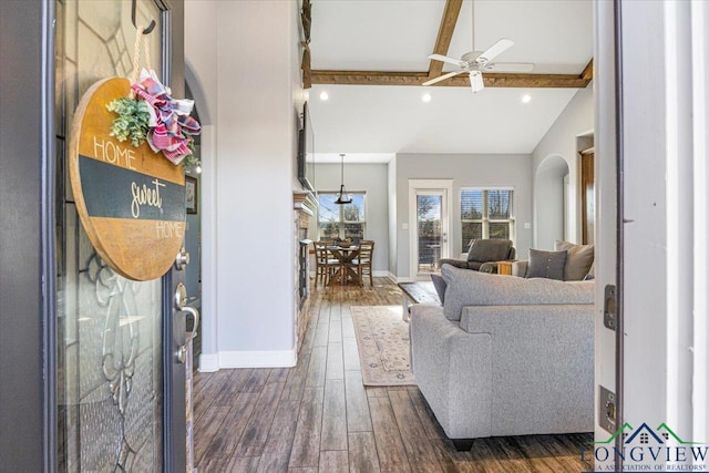 living room featuring lofted ceiling with beams, ceiling fan, and dark wood-type flooring