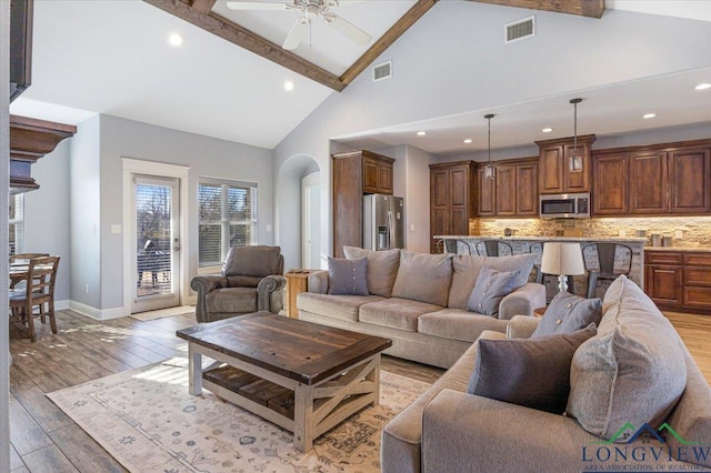 living room featuring ceiling fan, beamed ceiling, high vaulted ceiling, and hardwood / wood-style flooring