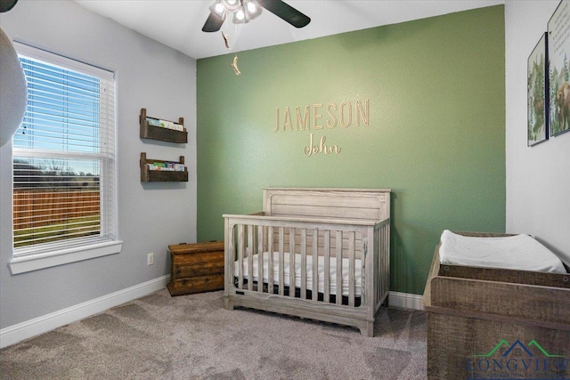 bedroom featuring ceiling fan, a crib, carpet floors, and multiple windows