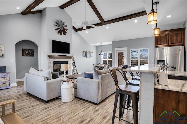 living room with beam ceiling, ceiling fan, and high vaulted ceiling